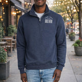 A man wearing a navy blue sweatshirt with the text "YOUR LOCAL GOES HERE" printed on it stands on a sidewalk in front of a building with string lights.
