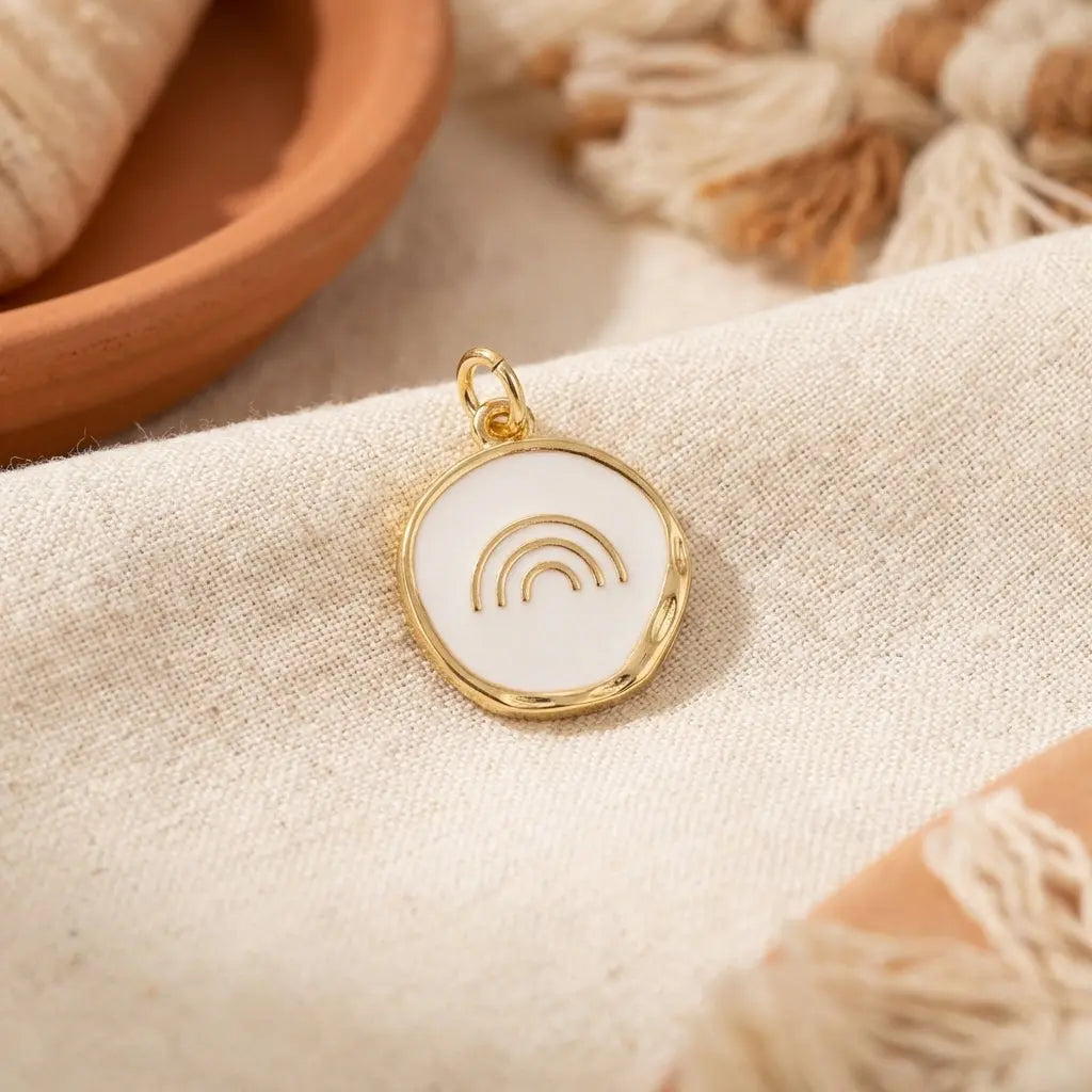Gold over the rainbow disc charm by Winks Design Studio, LLC, featuring a colorful rainbow design on a round metal charm.
