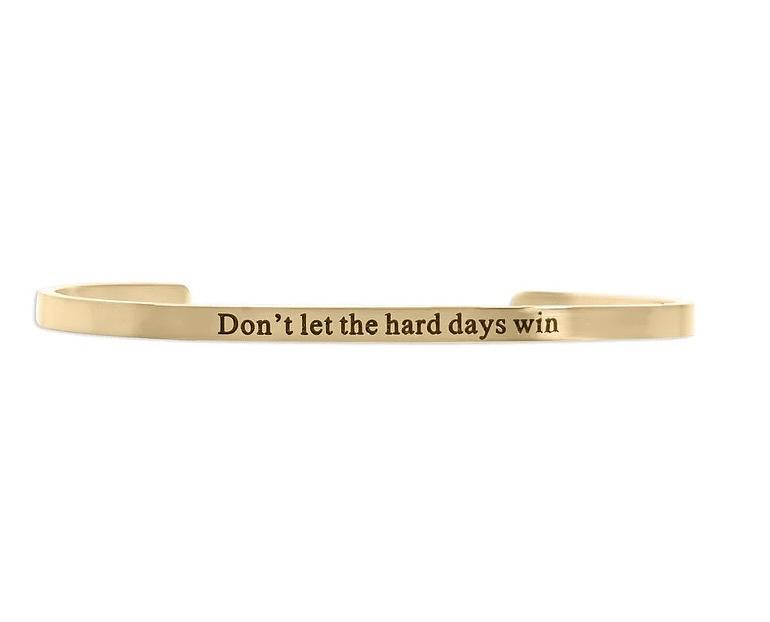 Gold bracelet with motivational message on a white background