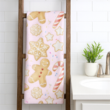 Towel with gingerbread man, snowflake, and candy cane pattern hanging on a wooden towel rack in a bathroom.