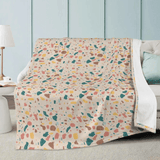 Terrazzo blanket with colorful patterns draped over a white couch, enhancing cozy and chic living room décor.