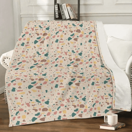 Terrazzo blanket draped over white armchair in a stylish living room, blending luxury and convenience with plush fleece material for a cozy feel