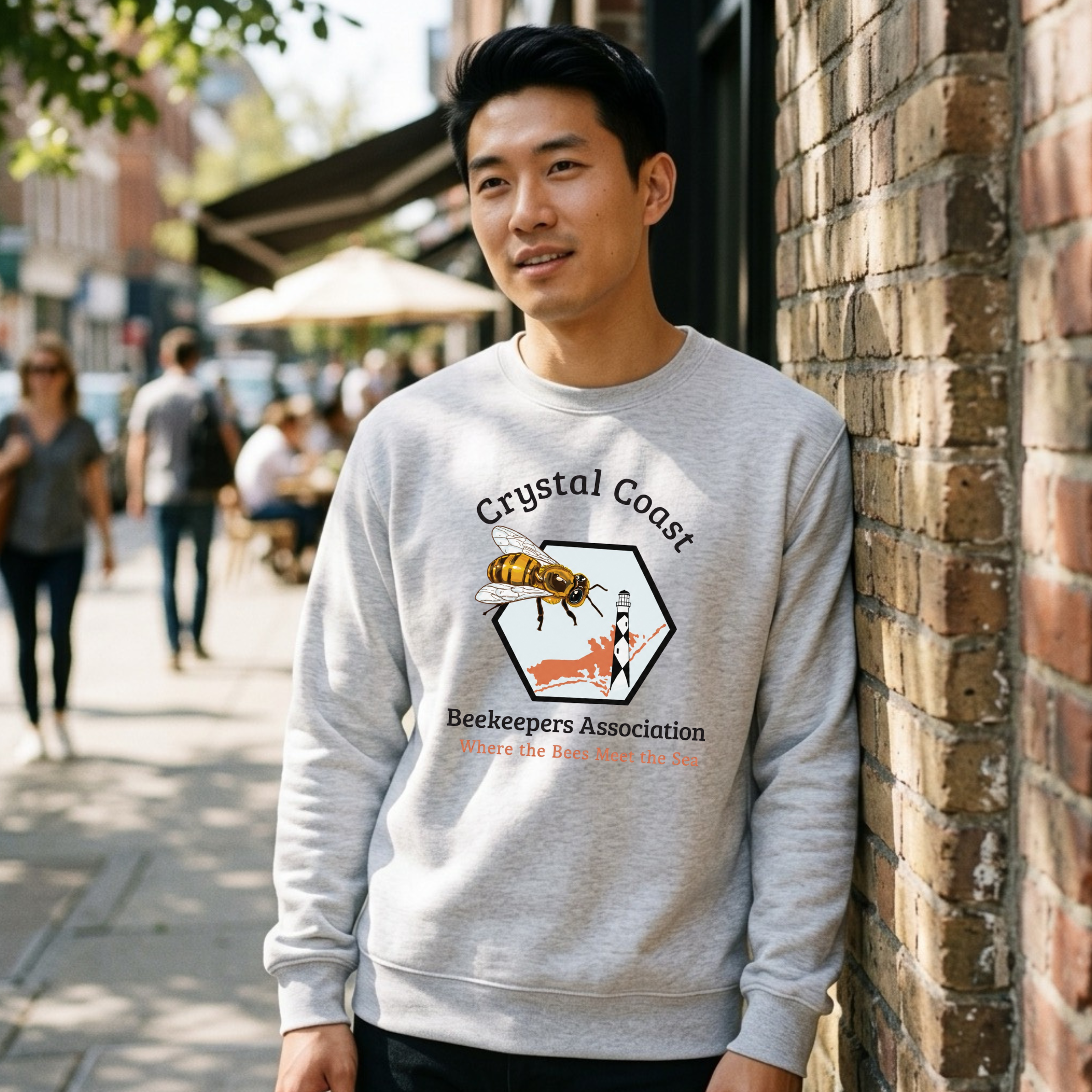 Cream-colored crewneck sweatshirt featuring a Crystal Coast Beekeepers design by Winks Design Studio, LLC, with bee and honeycomb graphics.