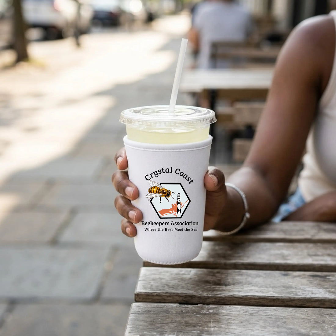 Crystal Coast Beekeepers neoprene cup sleeve featuring honey bee and floral design, providing insulation and style for beverage cups.