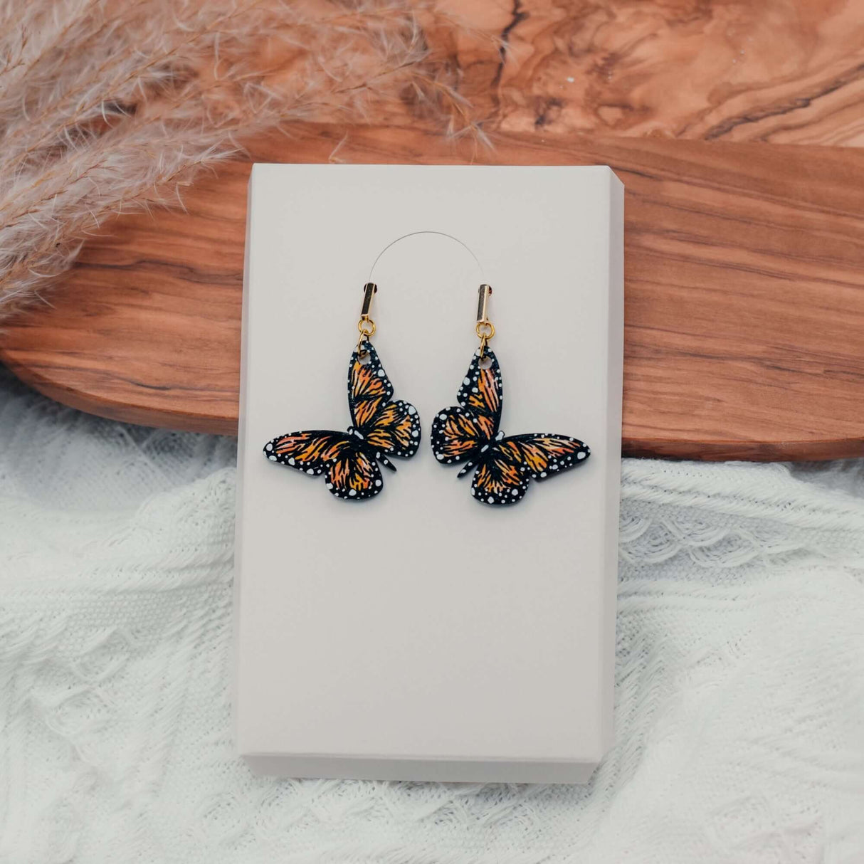 Hand-painted wooden butterfly earrings with vibrant colors on a display box.