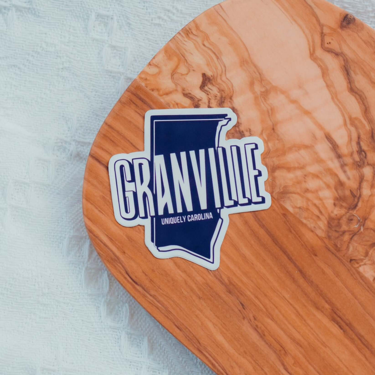 Granville NC Uniquely Carolina Sticker on wooden surface, showcasing local pride with durable vinyl design.