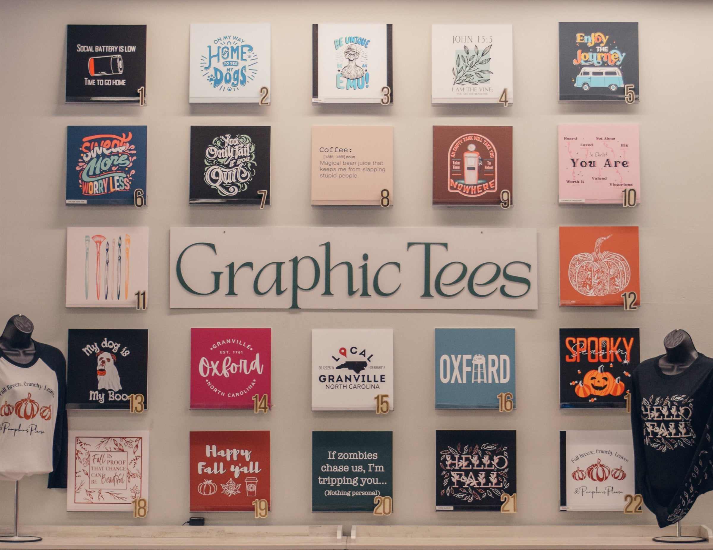 Display of various graphic tees on a wall with 'Graphic Tees' sign.