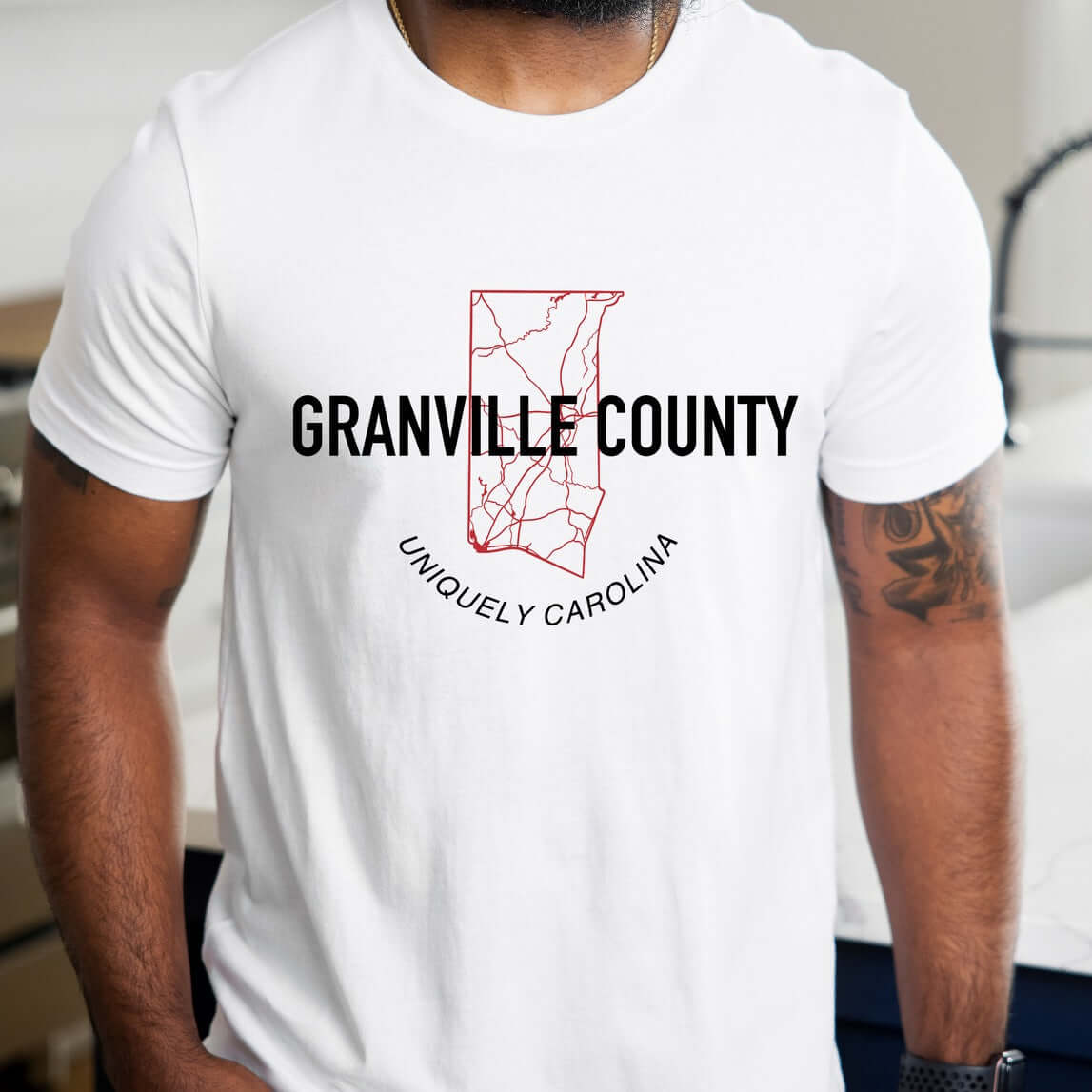 Man wearing Granville County Map Outline T-Shirt with red detailed outline map design and text "Granville County Uniquely Carolina" on white tee