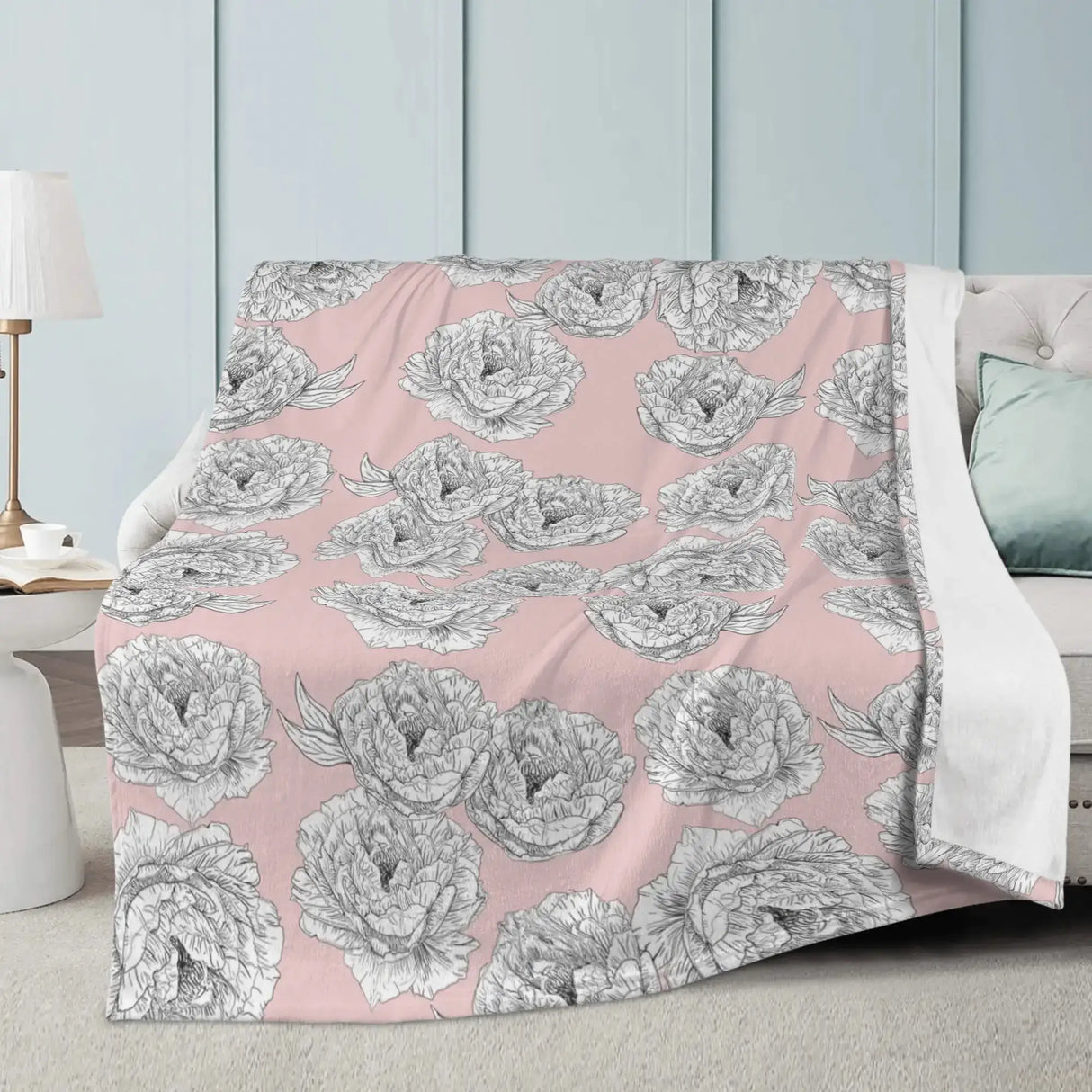 Pink Peony Flower Blanket with hand-drawn peony pattern, draped over a white sofa in a minimalist living room setting.