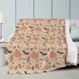 Pumpkin Patch Fall-Themed Blanket with pumpkins, pie, and leaves pattern draped on a white sofa in a cozy living room.