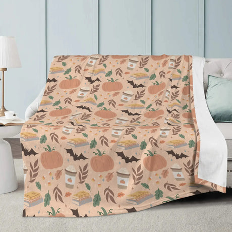 Pumpkin Patch Fall-Themed Blanket with autumn design featuring pumpkins, pie, and leaves on a cozy sofa.