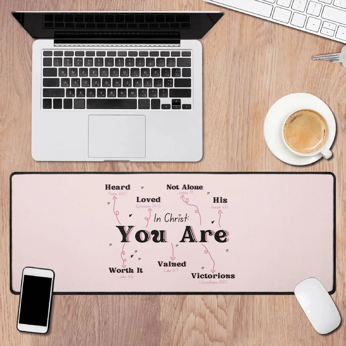 In Christ You Are desk mat on wooden desk with laptop, smartphone, coffee, and keyboard, designed for motivation and comfort.