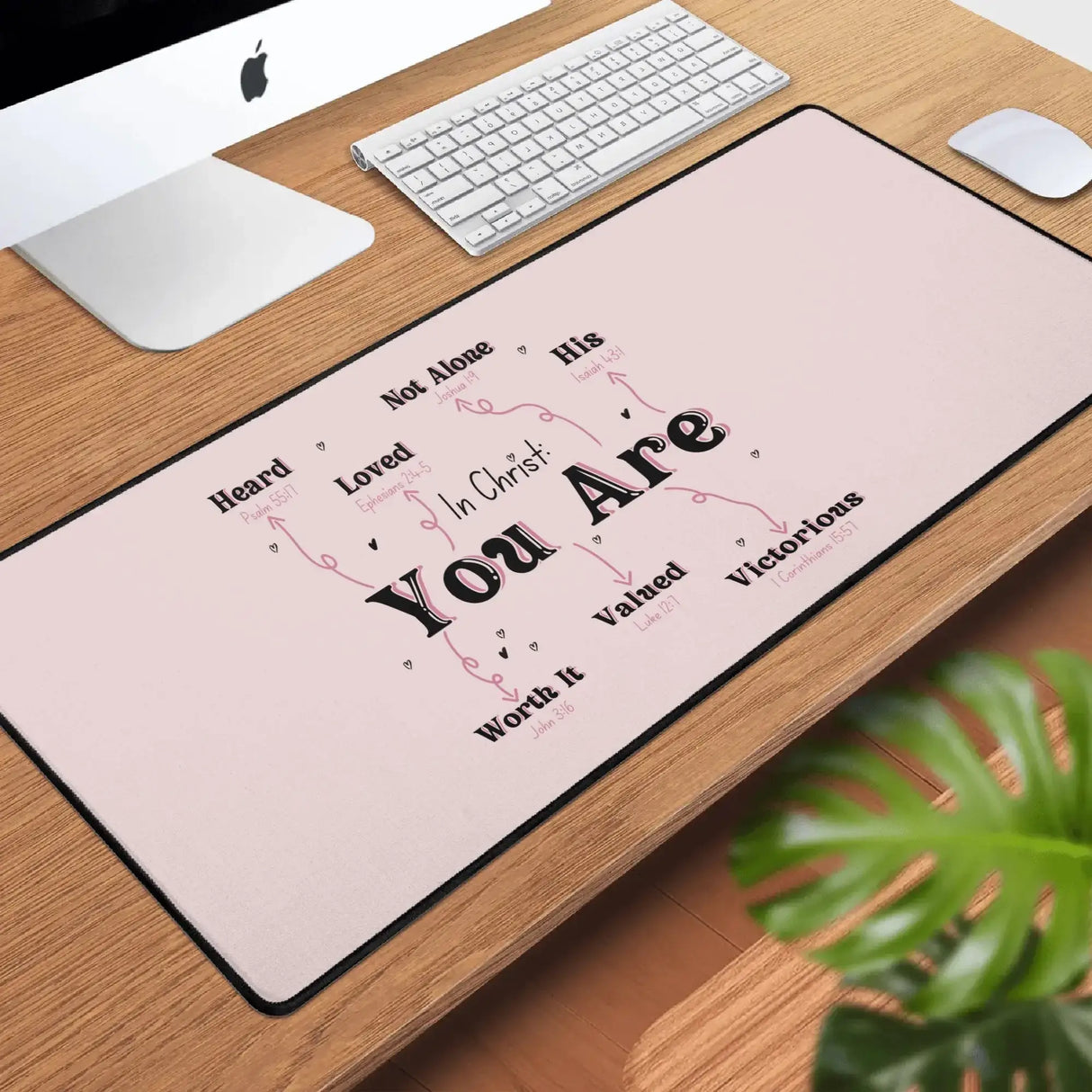 In Christ You Are desk mat on wooden desk with keyboard, mouse, and plant, providing inspiration and motivation for your workspace.