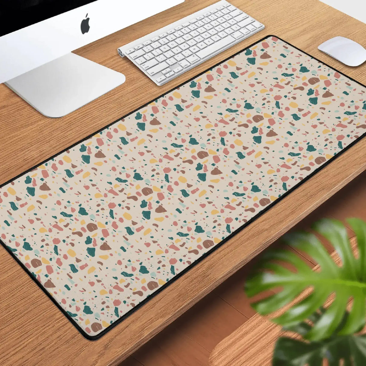 Terrazzo Desk Mat on wooden desk with computer, keyboard, mouse, and plant in workspace setup.