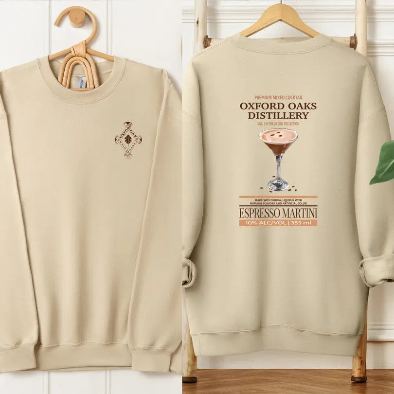 Cream-colored crewneck sweatshirt featuring Oxford Oaks Distillery Espresso Martini logo, comfortable casual style from Winks Design Studio.