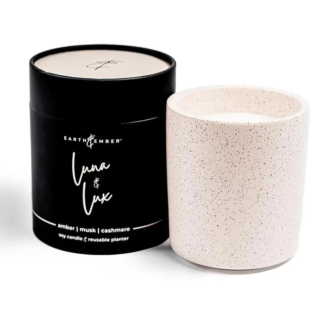 Earth &amp; Ember Luna &amp; Lux 13 oz candle by Winks Design Studio, LLC, with a sleek glass container and a lit wick inside.