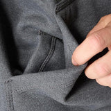 Close-up of a hand adjusting the hem of gray pants.