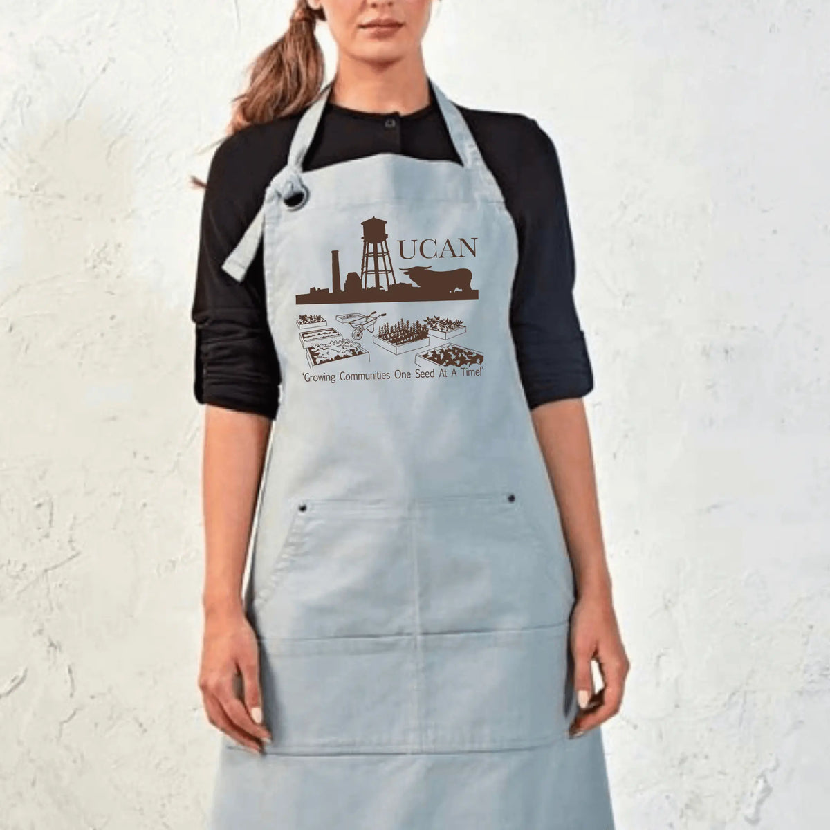 Black UCAN Pocketed Garden Apron by Winks Design Studio, LLC, with multiple pockets for gardening tools and accessories.