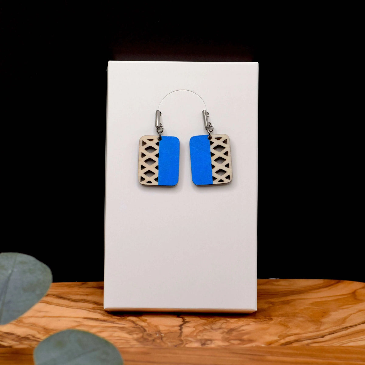 Colorful geometric wooden earrings by Winks Design Studio, LLC featuring vibrant blue shapes and natural wood textures.