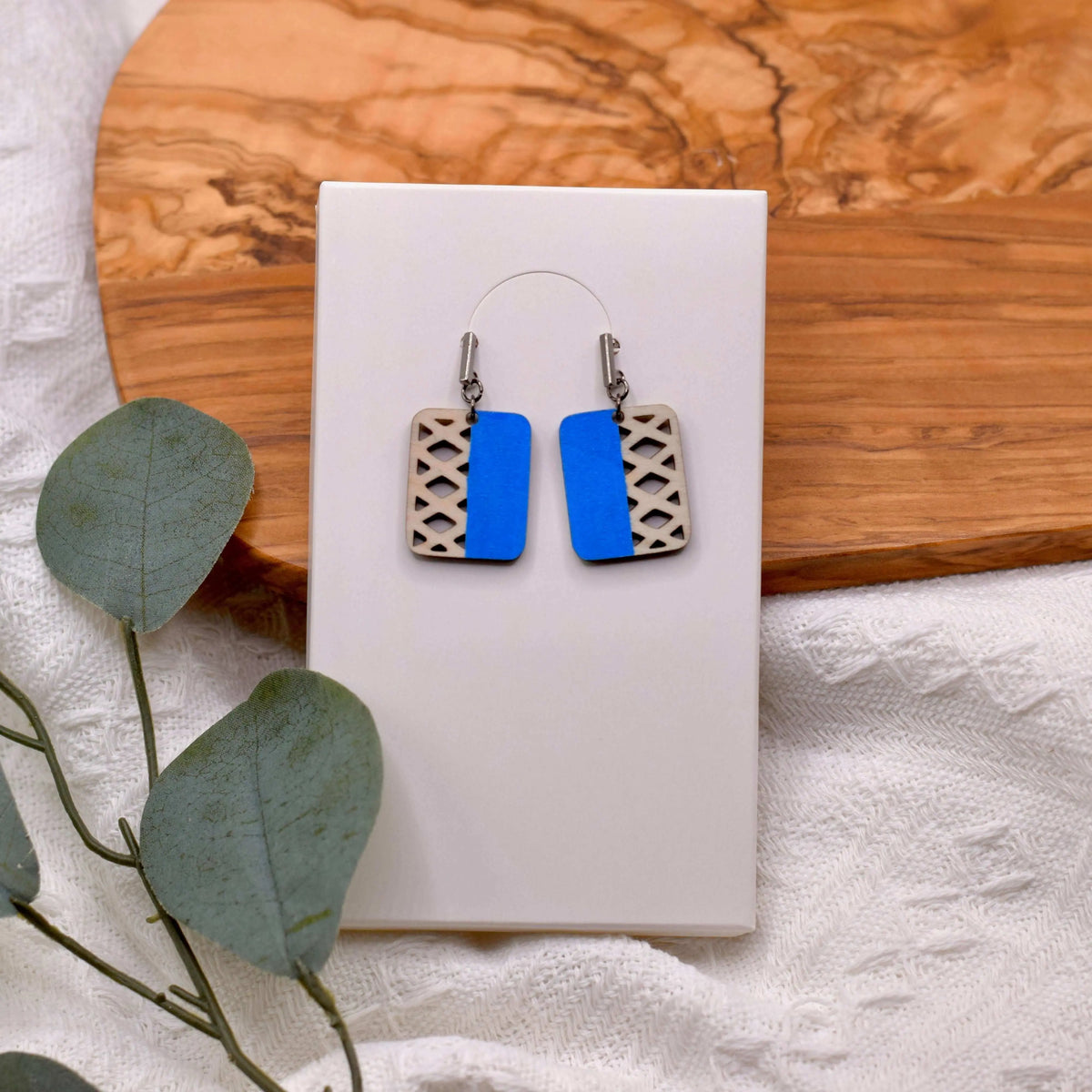 Colorful geometric wooden earrings by Winks Design Studio, LLC with vibrant blue and multicolor shapes, lightweight and stylish.