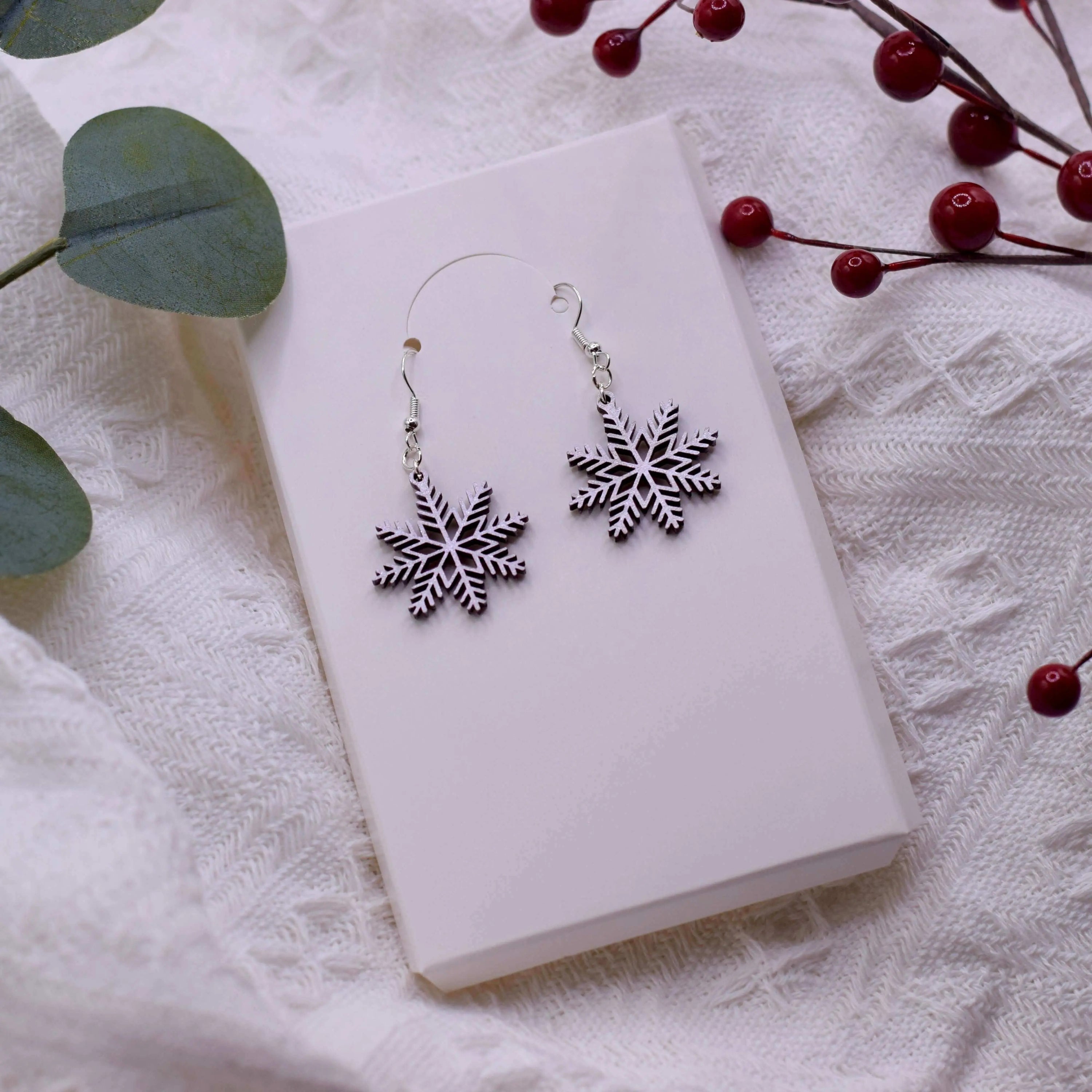 Wooden shimmering snowflake earrings by Winks Design Studio, LLC, featuring intricate snowflake shapes with a sparkling finish.