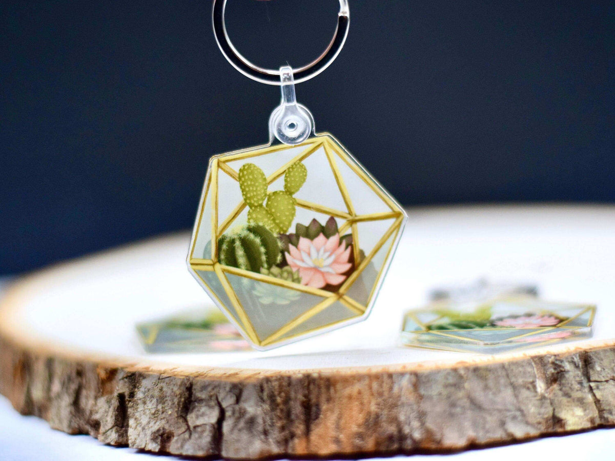Acrylic keychain featuring a miniature succulent terrarium design by Winks Design Studio, LLC, with vibrant green plants inside a transparent case.