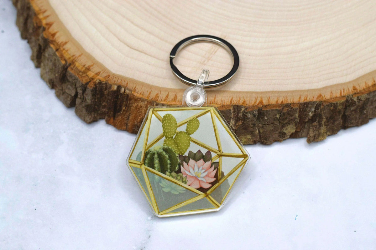 Acrylic keychain featuring a realistic succulent terrarium design, branded by Winks Design Studio, LLC.