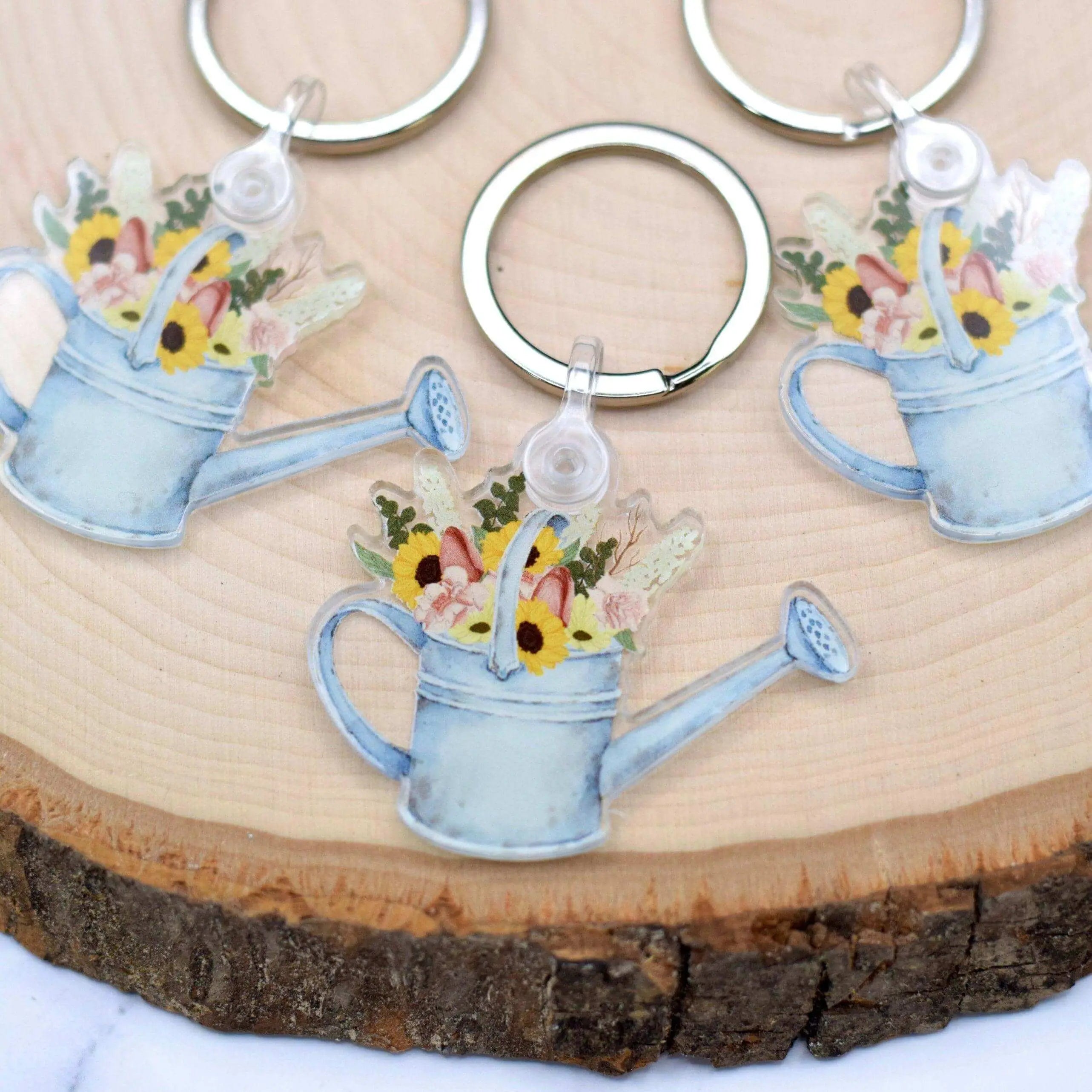 Winks Design Studio LLC watering can keychain with colorful flower charms, detailed metal design, and small hanging loop.