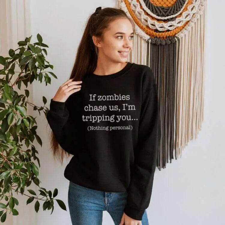 Winks Design Studio long sleeve shirt with humorous "If Zombies Chase Us I’m Tripping You" print, featuring zombie-themed design.