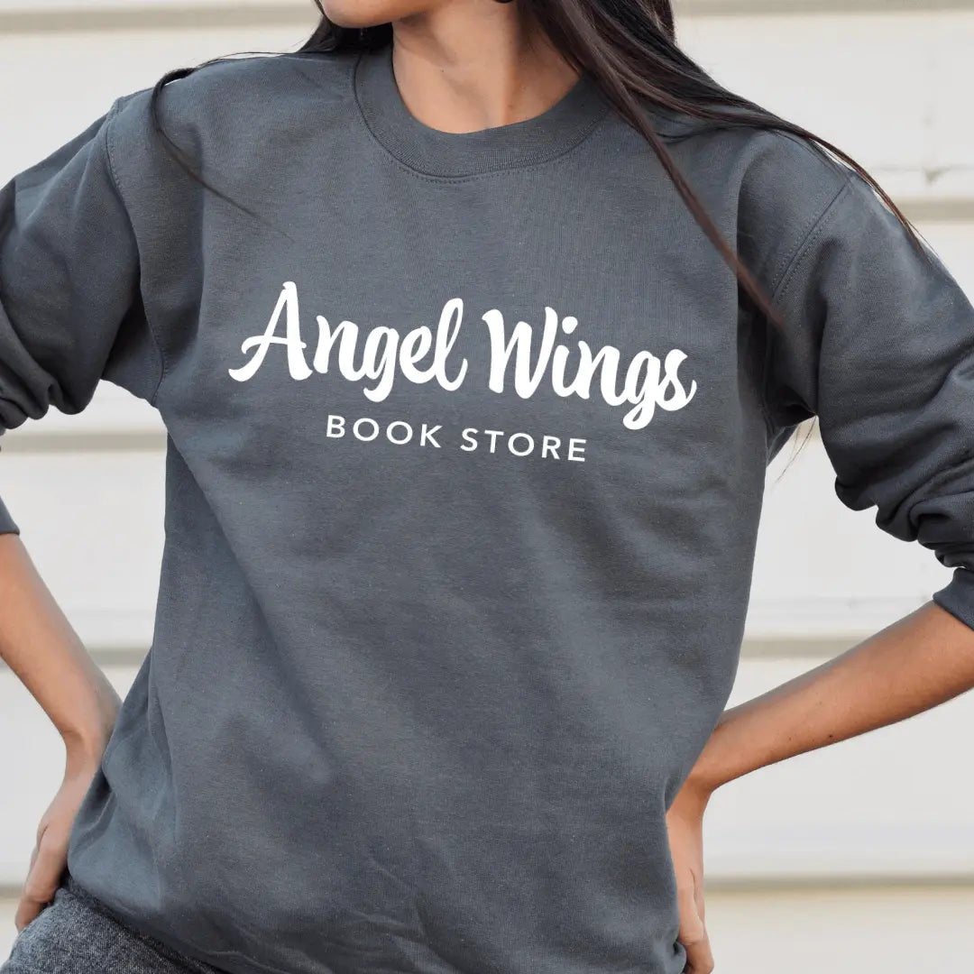 White long sleeve shirt with angel wings bookstore design by Winks Design Studio, LLC, displayed flat.