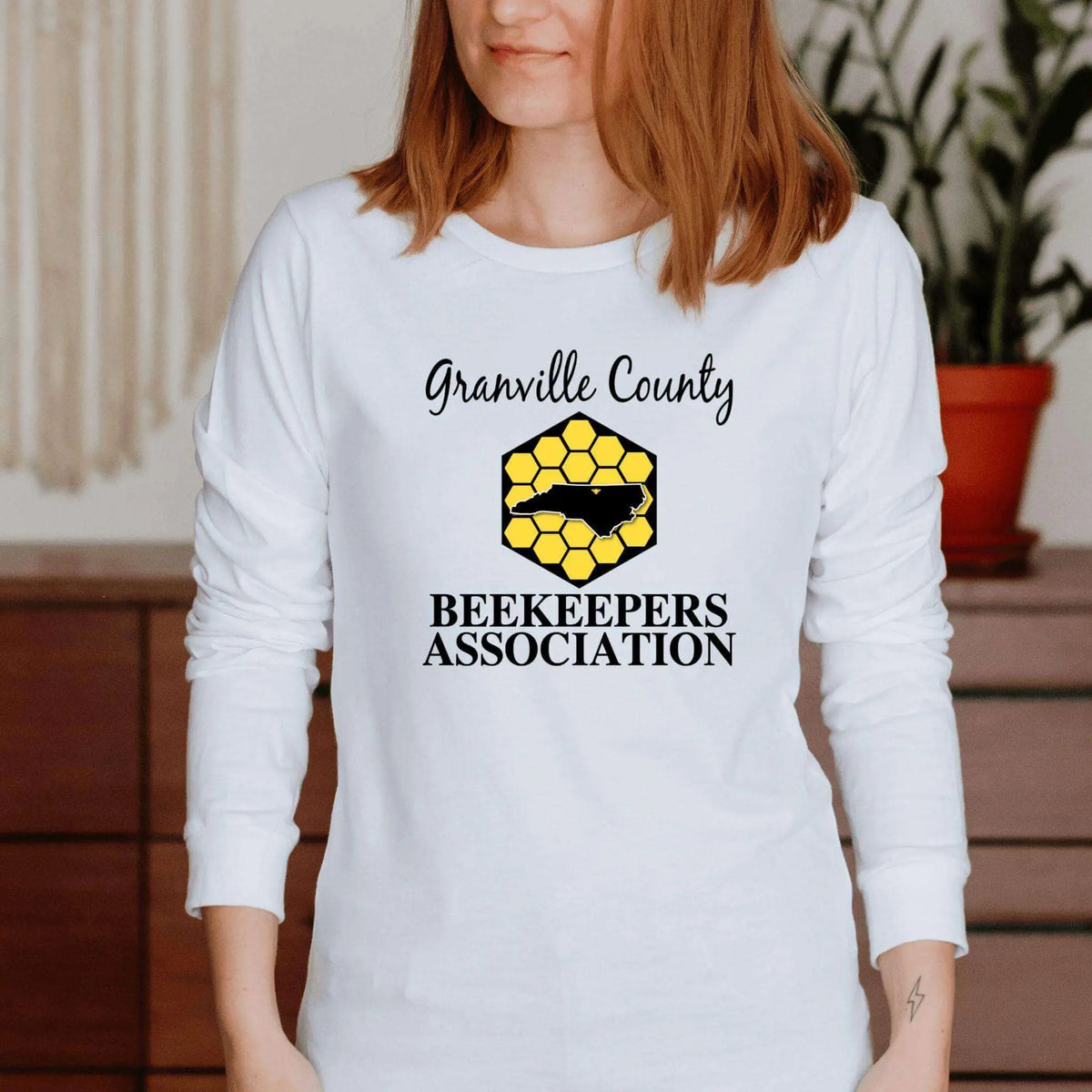 White long sleeve shirt with GCBA center chest image by Winks Design Studio, LLC, shown on a small-sized model.