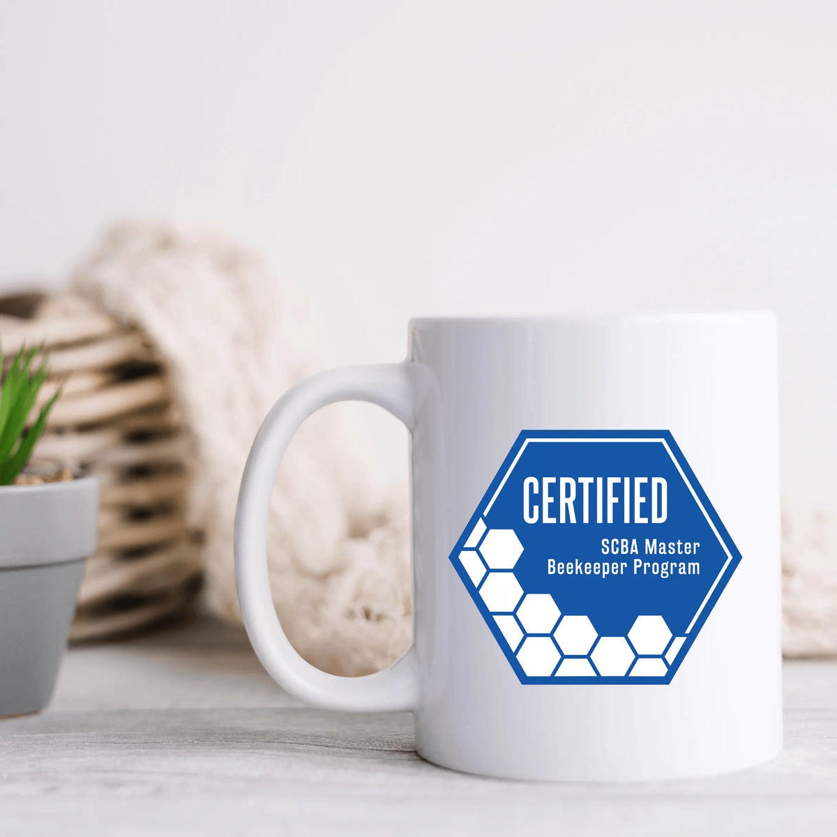 Ceramic mug featuring the SCBA Master Beekeeping Program design by Winks Design Studio, LLC, with detailed bee and hive artwork.
