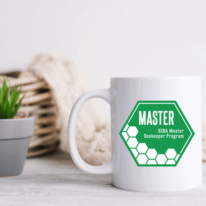 Ceramic mug with SCBA Master Beekeeping Program branding, featuring a beekeeping theme and Winks Design Studio logo.