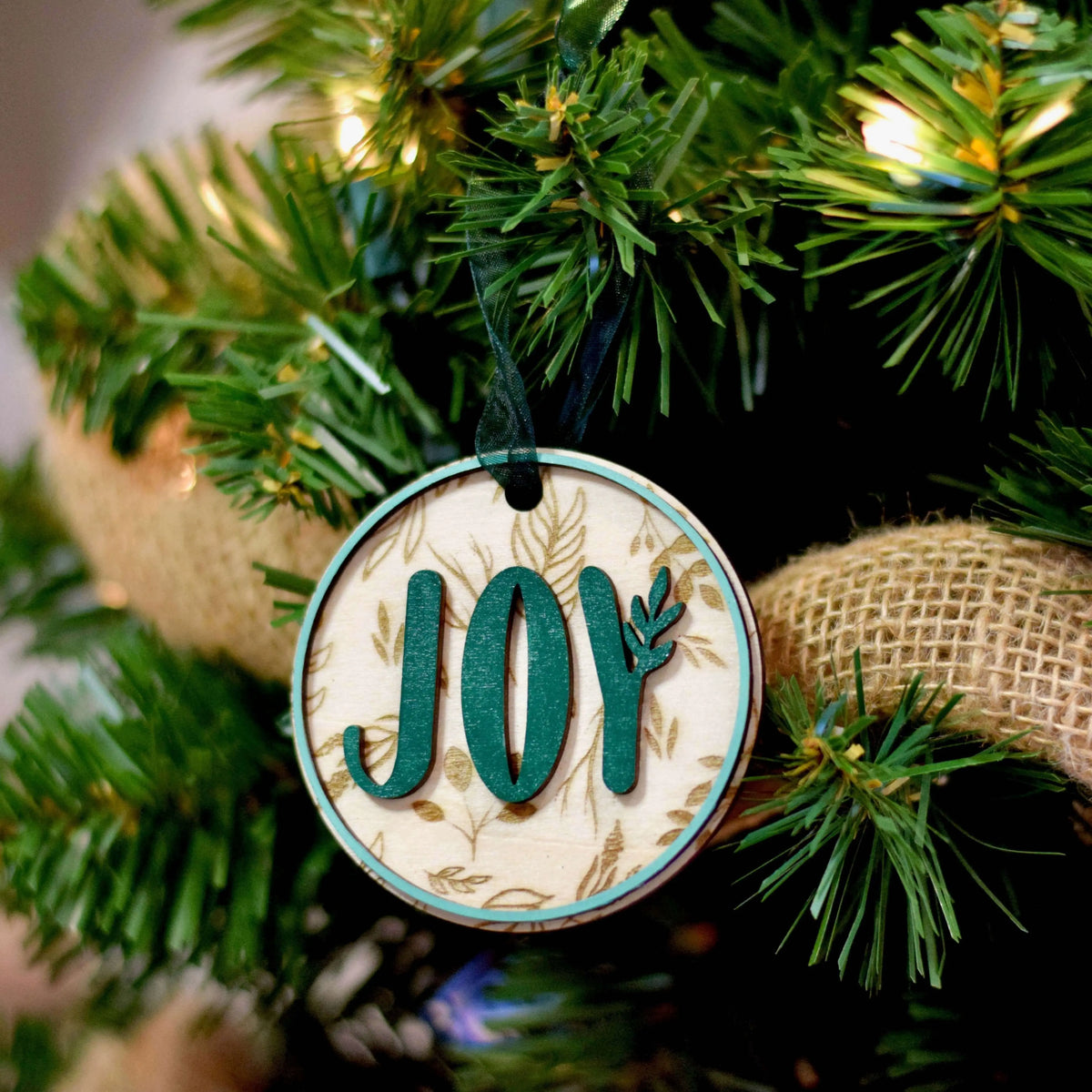 Wood engraved Joy ornament by Winks Design Studio, LLC featuring detailed craftsmanship and festive holiday design.