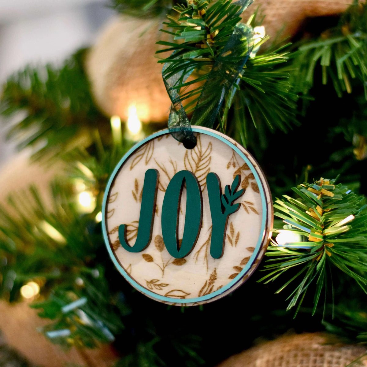 Wood engraved Joy ornament by Winks Design Studio, LLC featuring detailed festive design on natural wood surface.