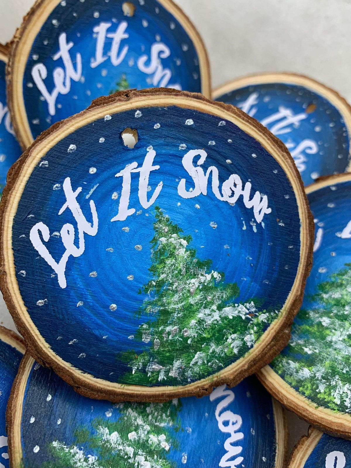 Hand-painted wood slice Christmas ornament with "Let it Snow" design by Winks Design Studio, LLC, featuring festive holiday artwork.