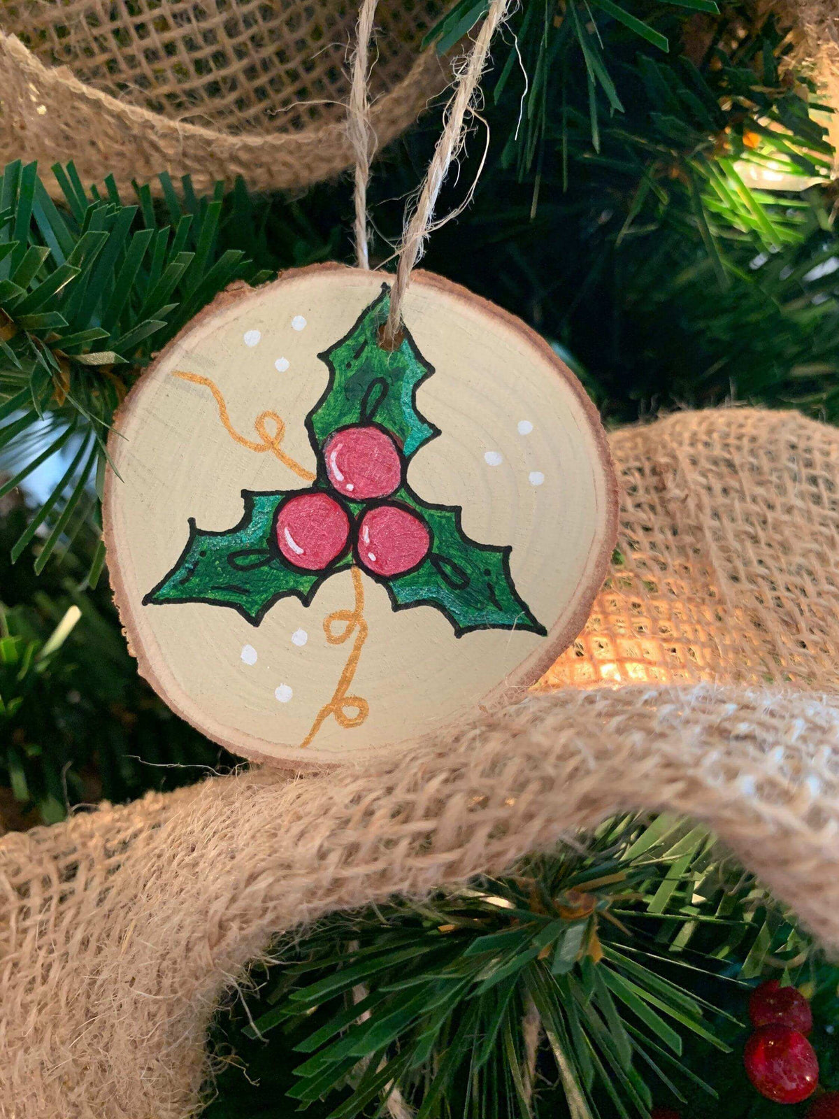 Christmas ornament featuring holly leaves and berries by Winks Design Studio, LLC, with detailed holly and berry decorations.