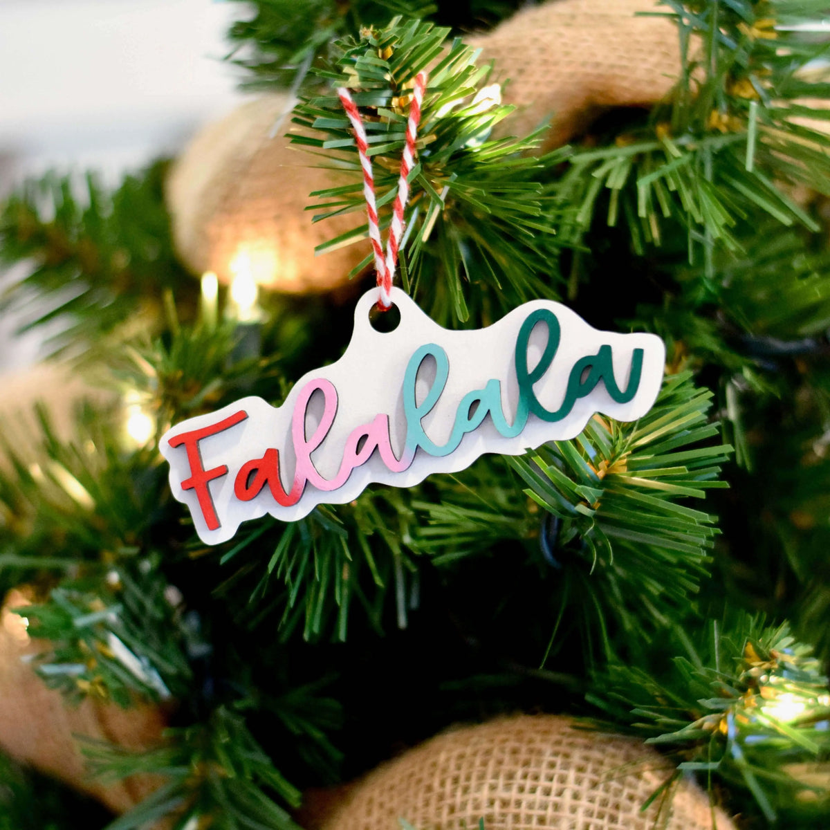 Engraved wooden ornament with "Falalala" design by Winks Design Studio LLC, featuring intricate carving on light wood.