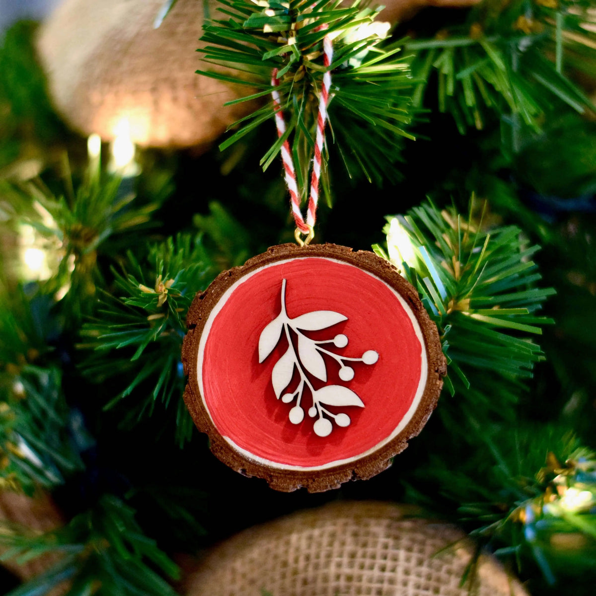 Red wooden floral ornament by Winks Design Studio, LLC, featuring detailed carved flower design on smooth wood surface.
