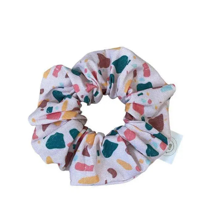 Terrazzo scrunchie by Winks Design Studio, LLC, made of fabric with a colorful terrazzo pattern for hair styling.