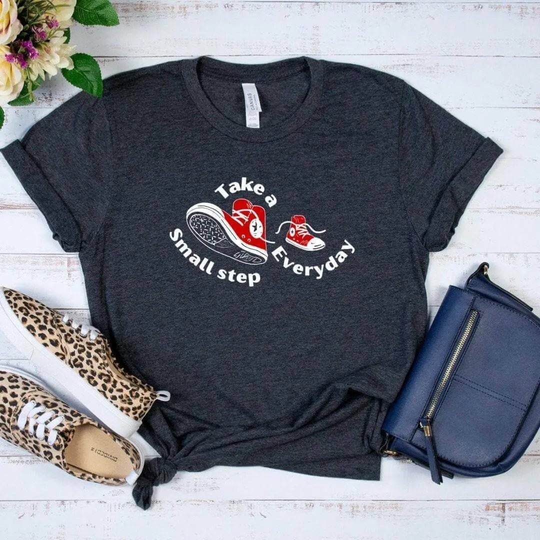 Black Take a Small Step Everyday T-Shirt from Winks Design Studio, LLC, featuring a casual fit and motivational design.