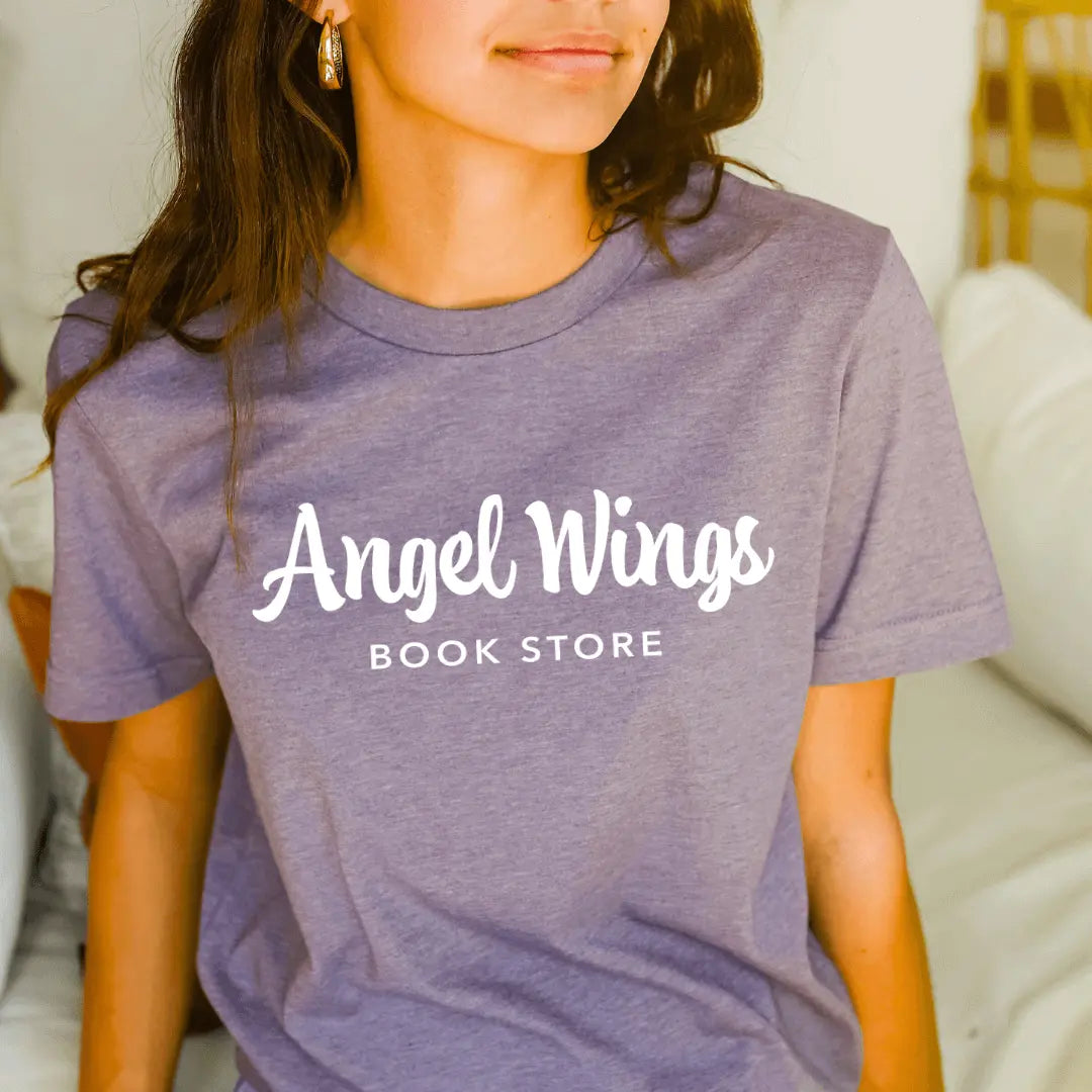 Heather purple T-shirt by Winks Design Studio with angel wings and bookstore horizontal graphic, casual unisex style.