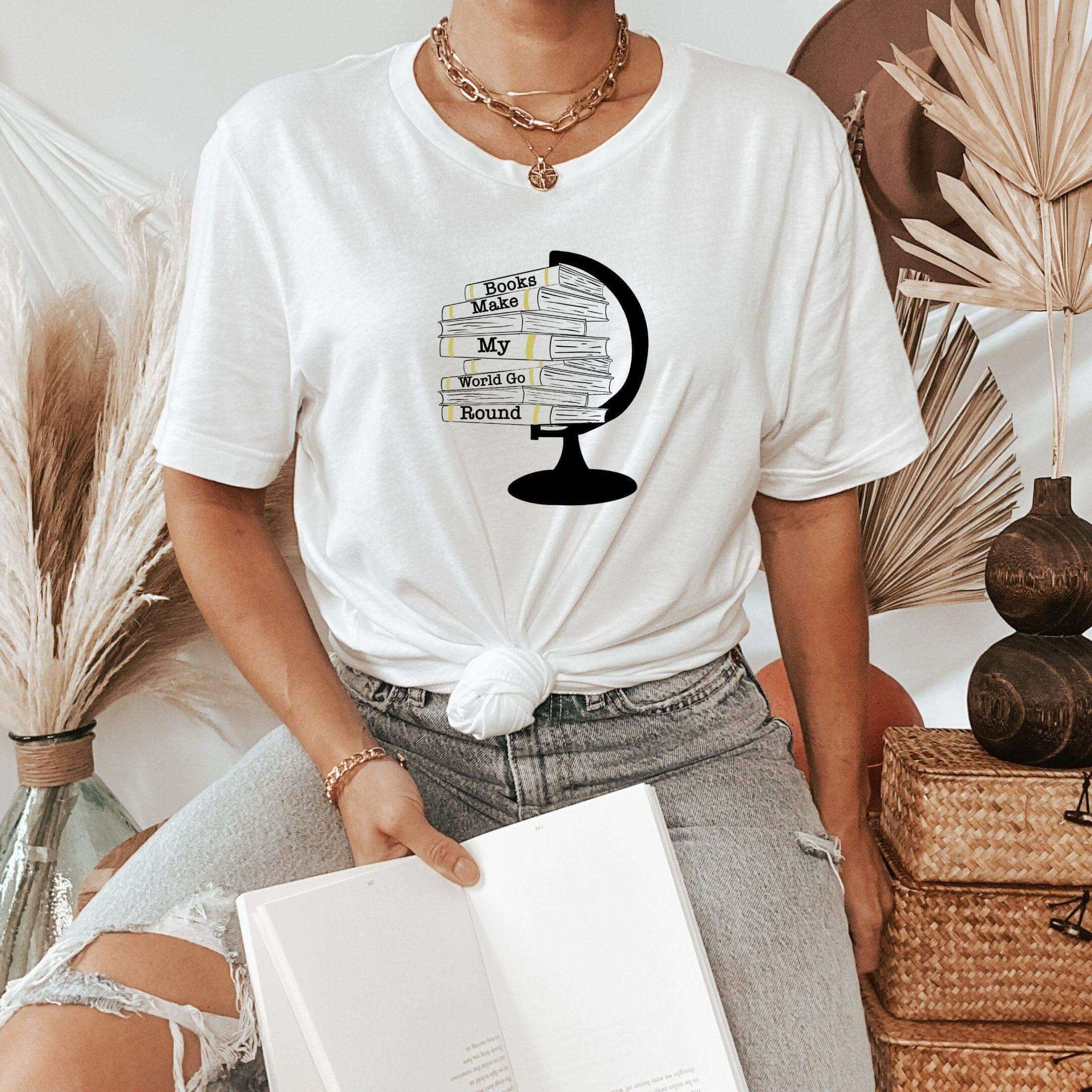 Winks Design Studio LLC T-shirt featuring a "Books Make My World Go Round" print, casual fit, soft fabric, and colorful book graphic.