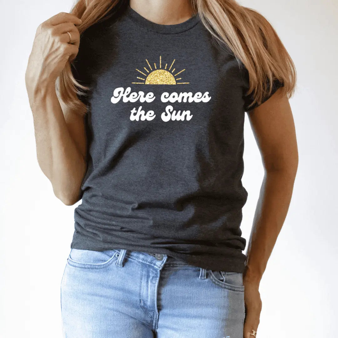 Winks Design Studio LLC Here Comes The Sun T-shirt with sun graphic and casual fit, made of soft cotton fabric.