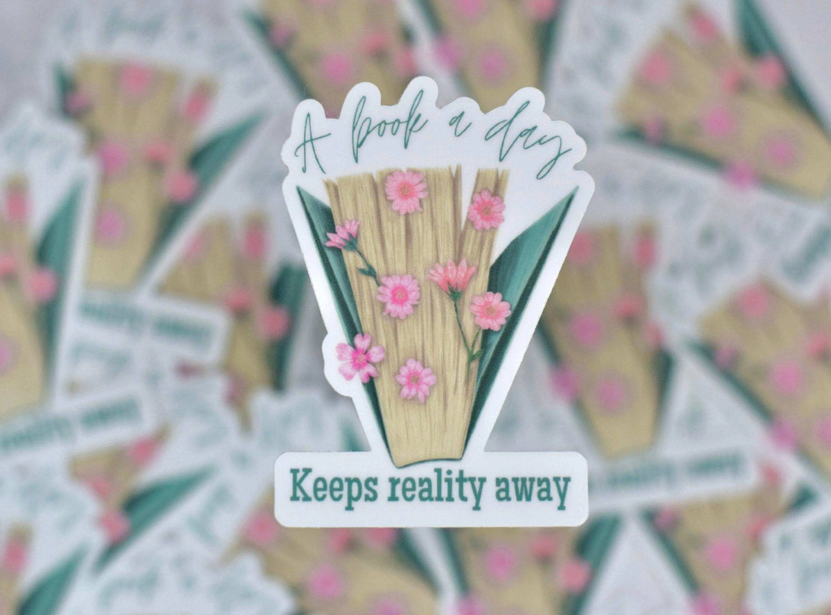Vinyl sticker by Winks Design Studio featuring the phrase "A Book a Day Keeps Reality Away" with book illustrations.
