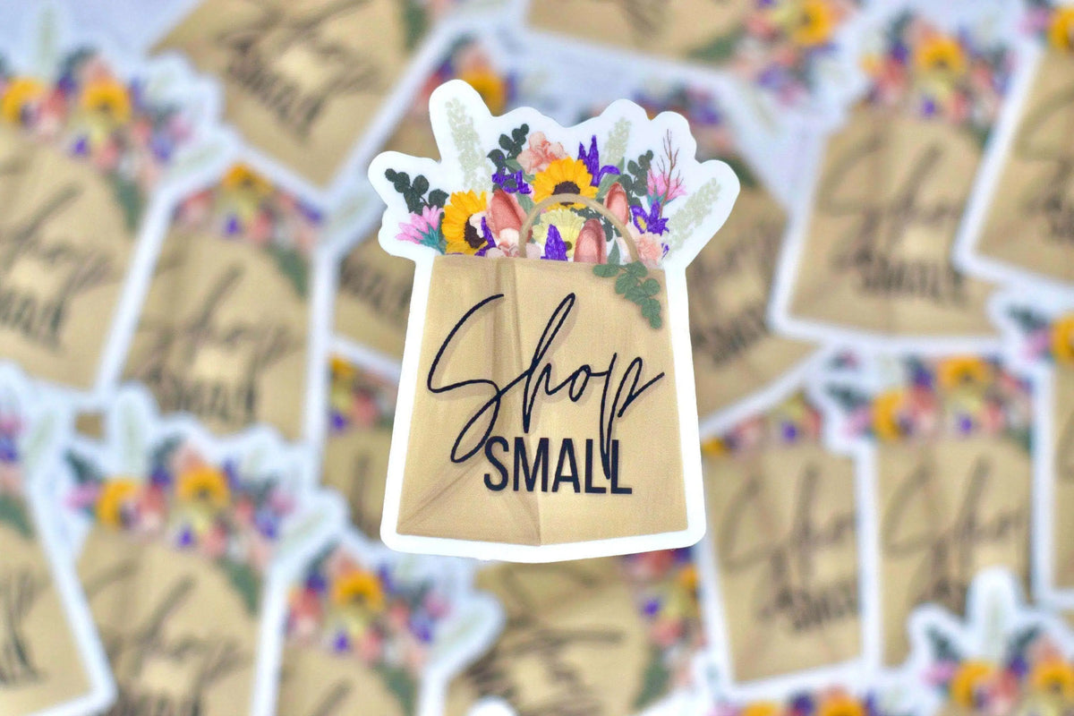 Small vinyl sticker featuring the "Shop Small" design by Winks Design Studio, LLC, with bold lettering on a clear background.